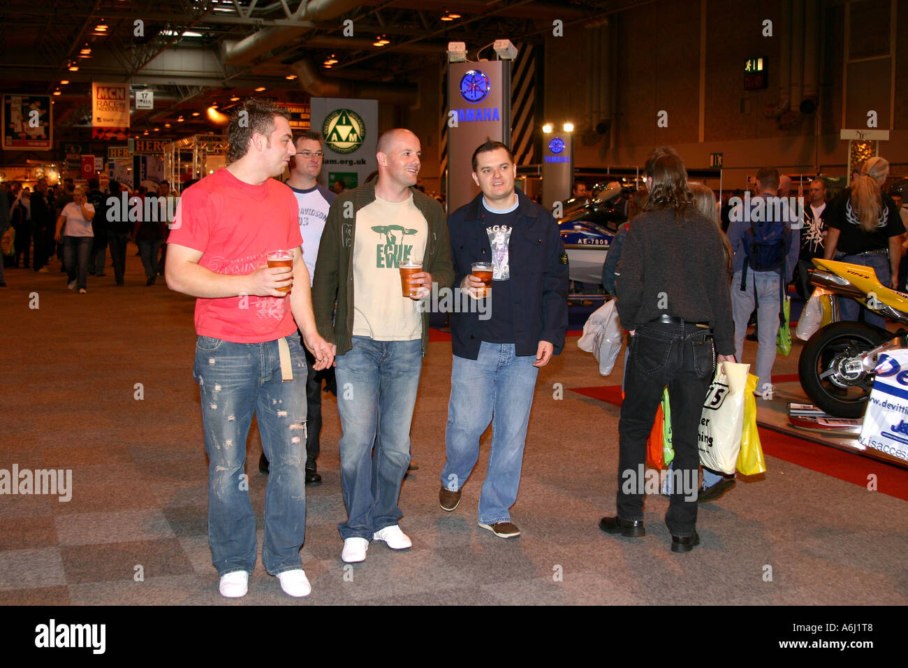 Un gruppo di uomini a piedi in occasione di una mostra con pinta bicchieri da birra nelle loro mani. Foto Stock