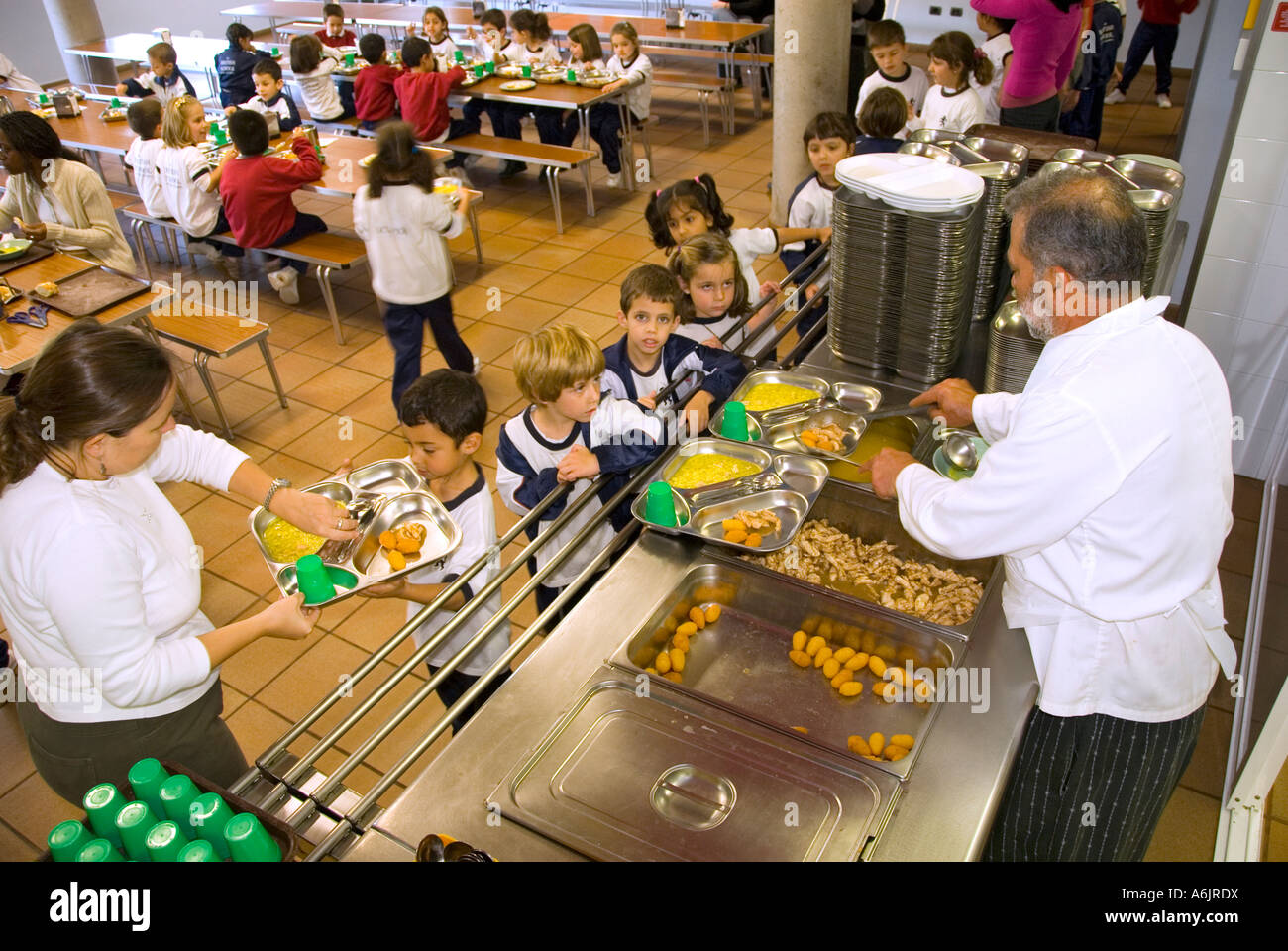 Scuola Cene pranzo servizio mensa popolare servente sana e bilanciata il pranzo a scuola per neonati bambini in mensa scolastica con chef e insegnante Foto Stock