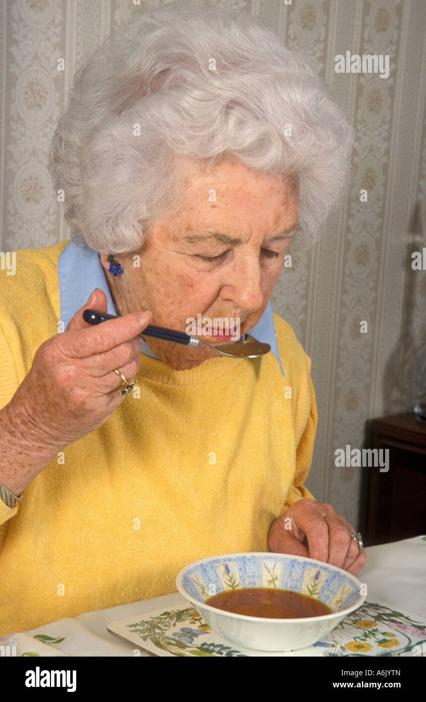 Donna anziana di mangiare la minestra Foto Stock