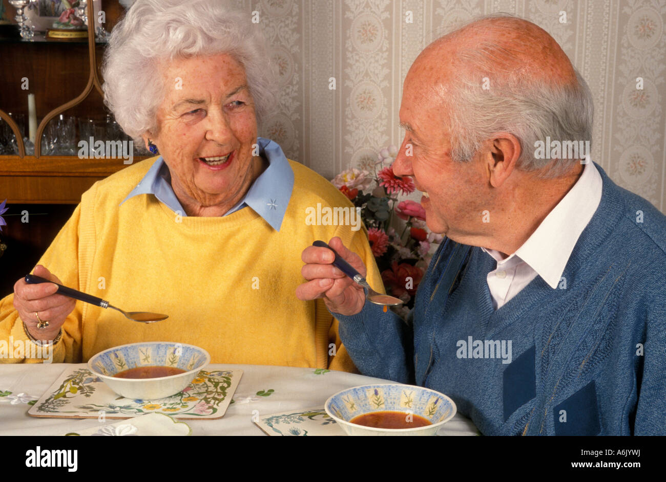 Felice coppia di anziani di mangiare la minestra al tavolo da pranzo Foto Stock