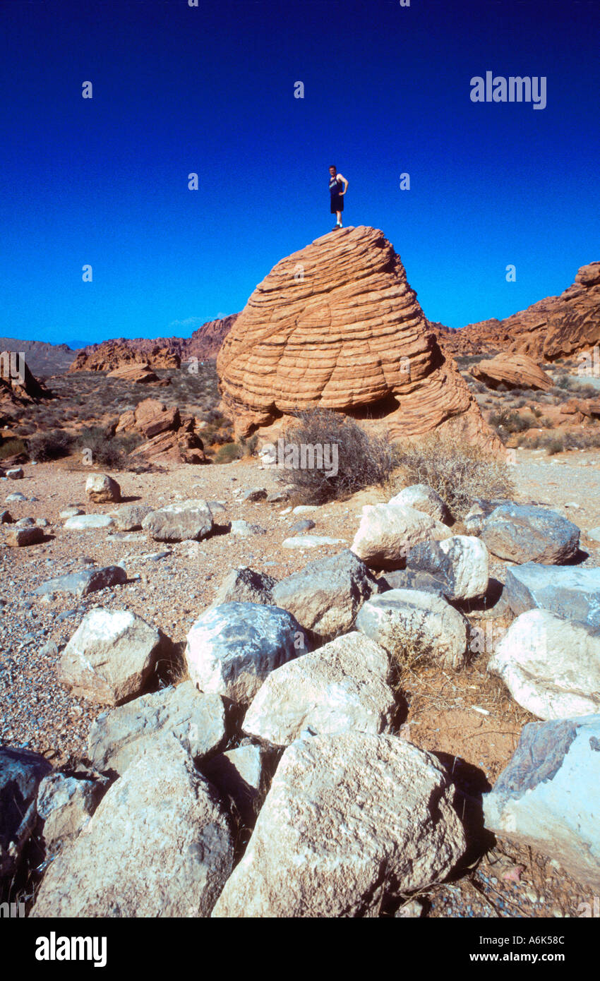 Nevada USA turista che visita il deserto " La Valle del Fuoco' uomo in piedi sul grande masso Avventura all'aperto Foto Stock