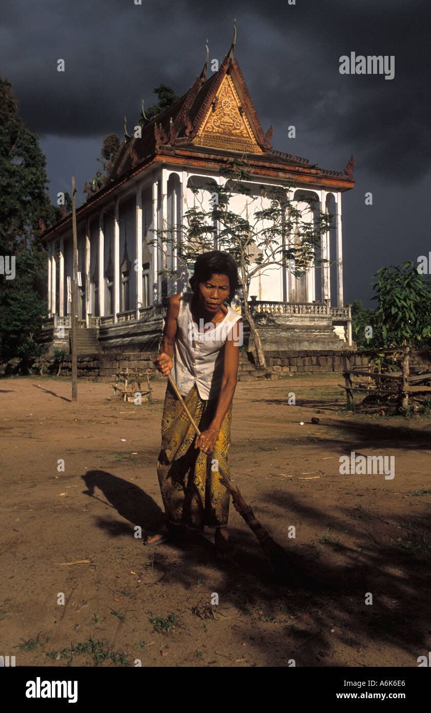 Cambogiani donna spazzare in presenza di luce solare al di fuori della pagoda nel villaggio Mohar come cielo nero mostra storm avvicinando Foto Stock
