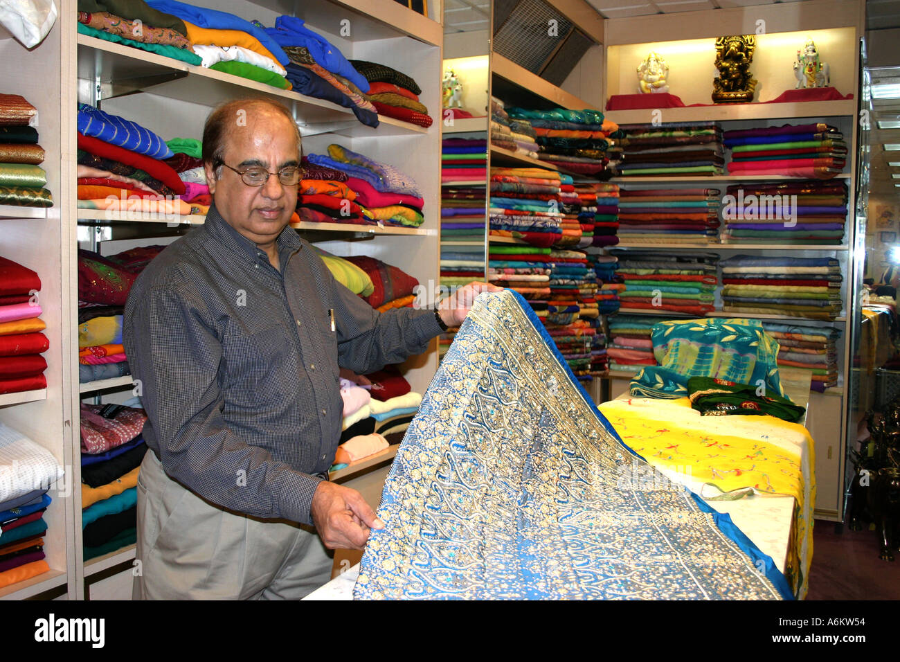 Indian proprietario di un negozio di Sari su Devon Street mostra tessuti, Chicago IL Foto Stock