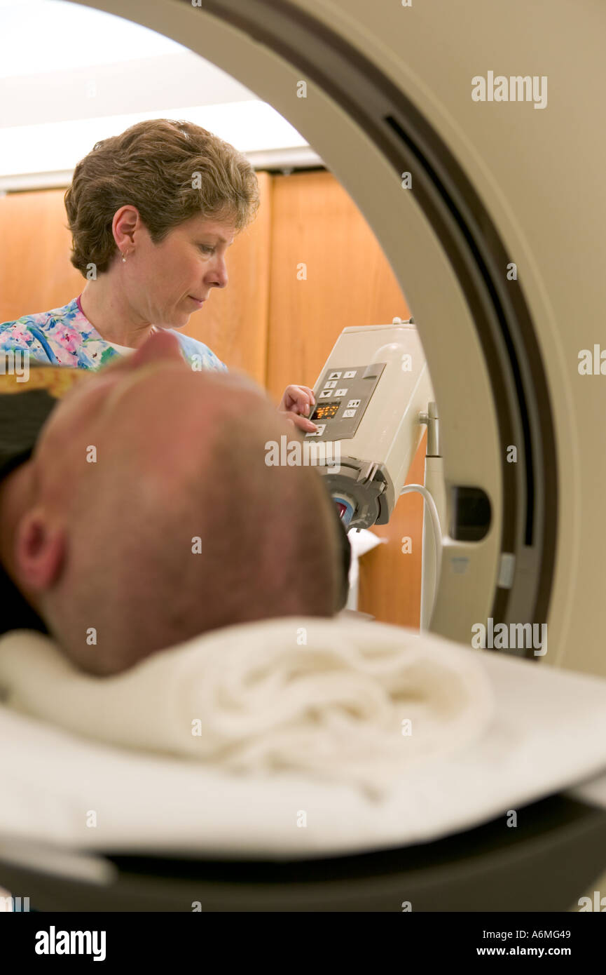 Aiuta il tecnico paziente scivolano attraverso CAT scansione che consente ai medici di fare una diagnosi Foto Stock