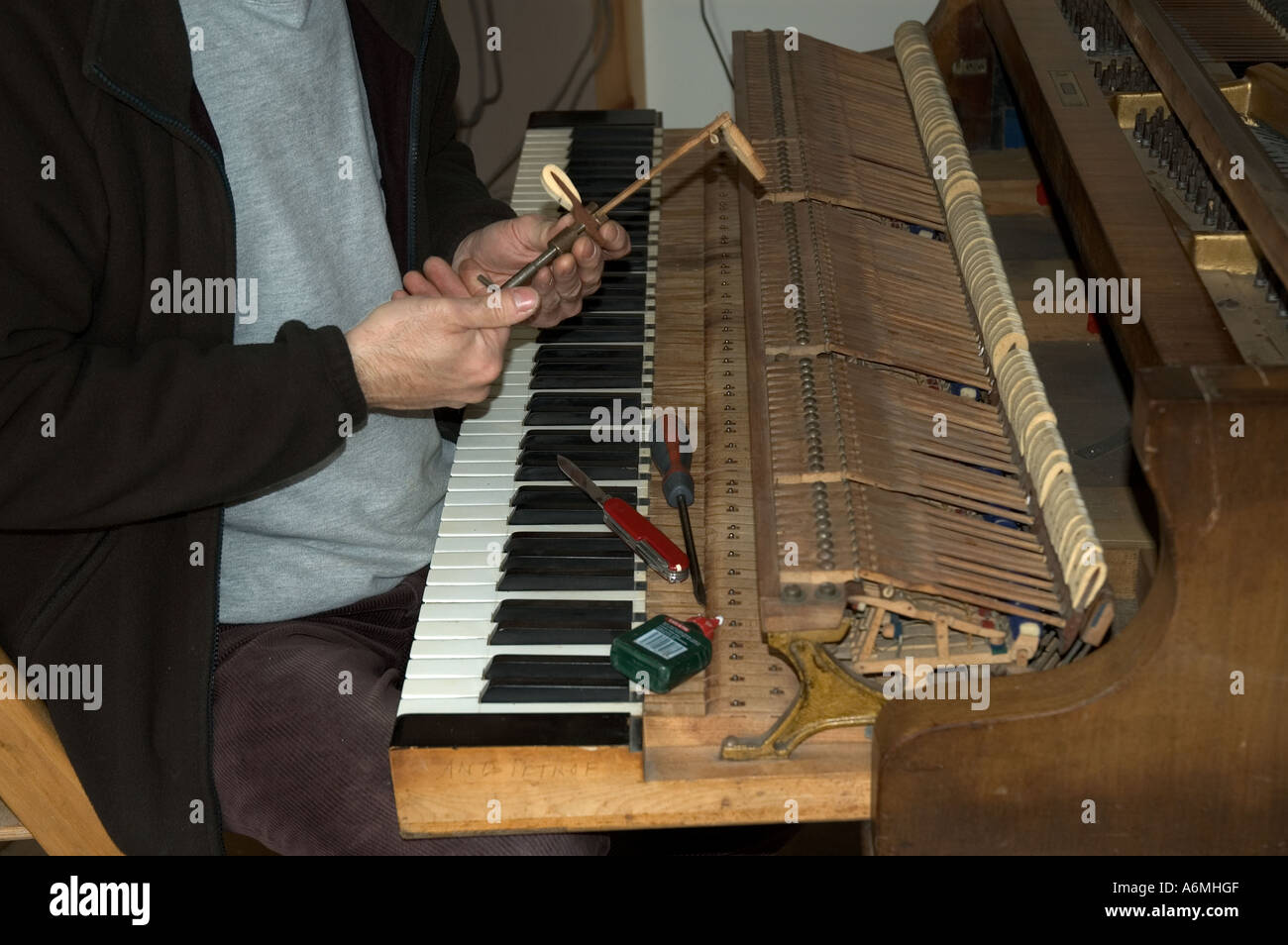 Un pianoforte renovator funziona su un baby grand piano Foto Stock