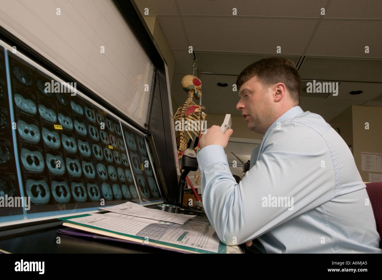 Maschio di valutazione da parte del radiologo di esami di lastre e di dettare le sue osservazioni e diagnosi Foto Stock