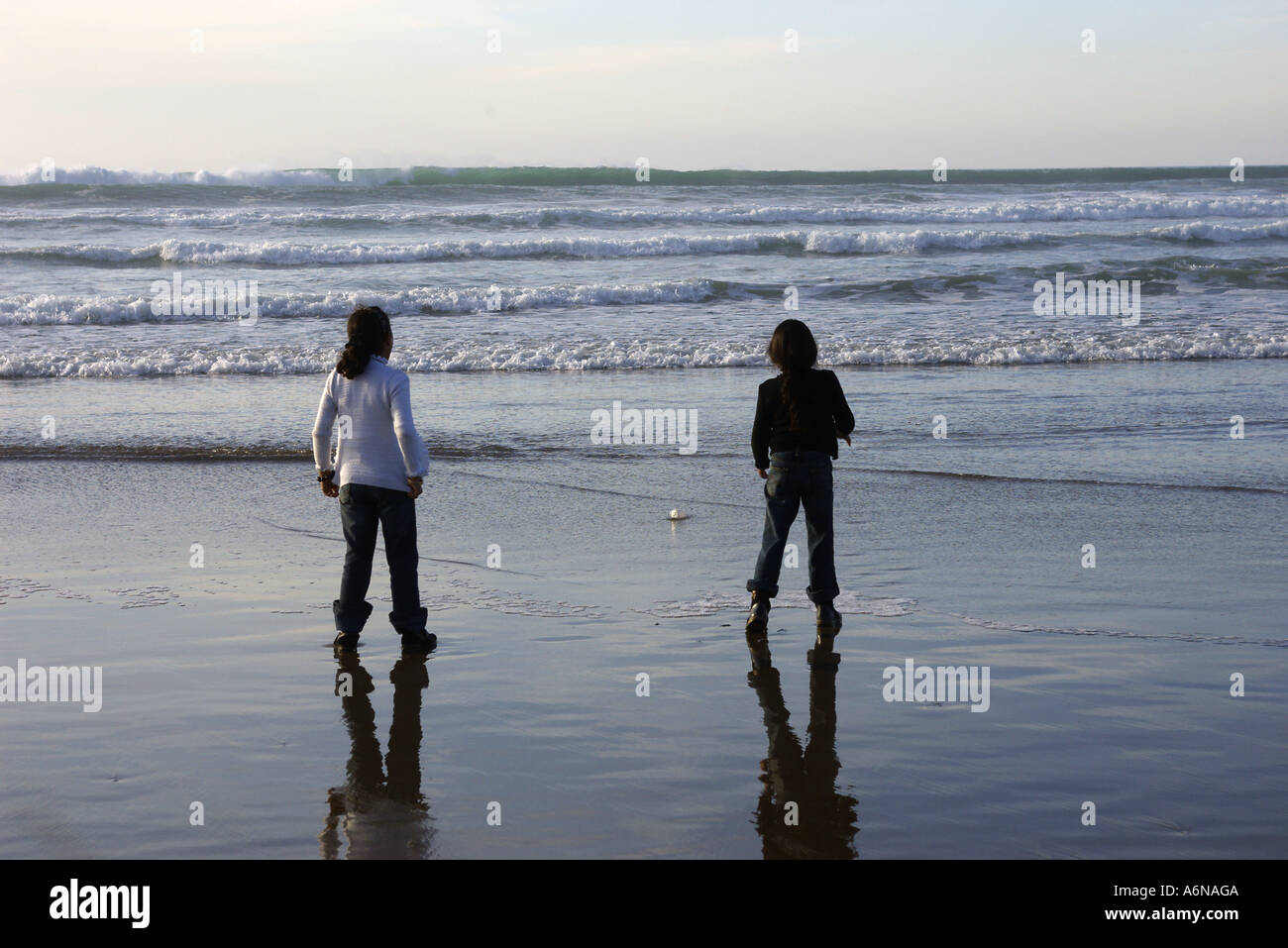 Due ragazze in spiaggia a giocare con le onde Foto Stock