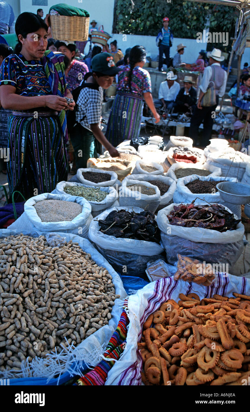 Maya donna che indossa un tessuto huipil sta in piedi in una produzione alimentare in stallo a Mercato San Martin Jilotepeque Guatemala Foto Stock