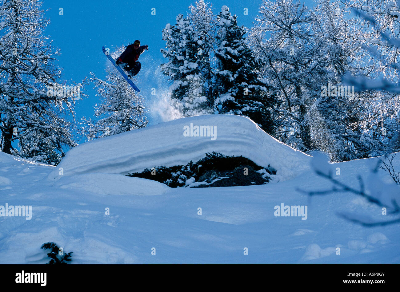 Snowboarder in un grab posizione che arriva fino al di sopra ar ripido crinale nevoso i fuori pista Foto Stock