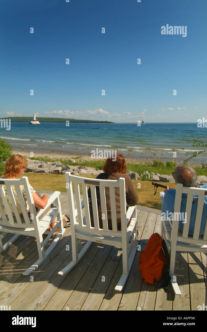 Stati Uniti Michigan isola di Mackinac Lago Huron tre adulti in seduta in legno Sedie a dondolo su un deck Foto Stock