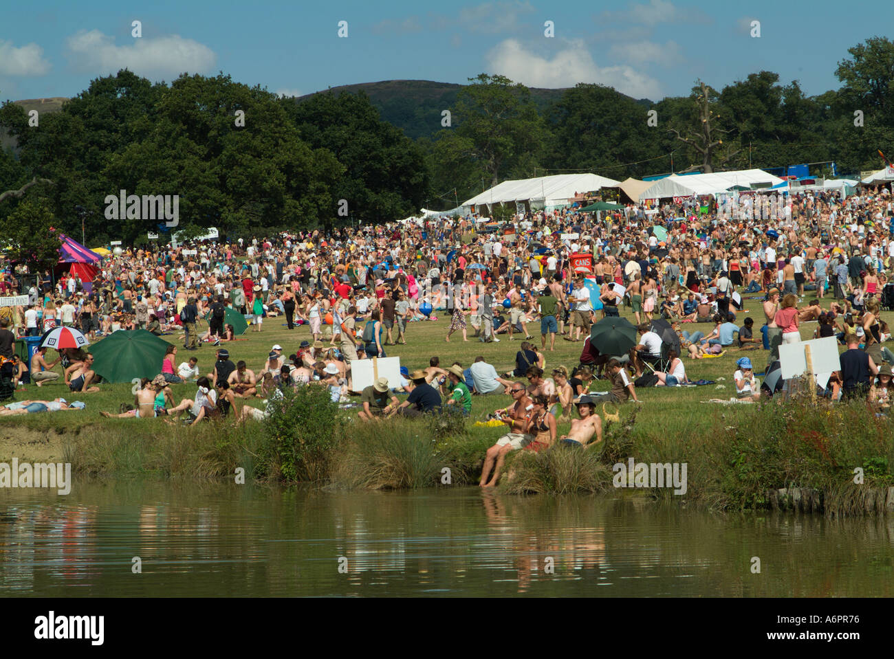 La folla dei frequentatori di partito si riflette nel lago al Big Chill festival di musica e danza il castello di Eastnor Herefordshire Foto Stock