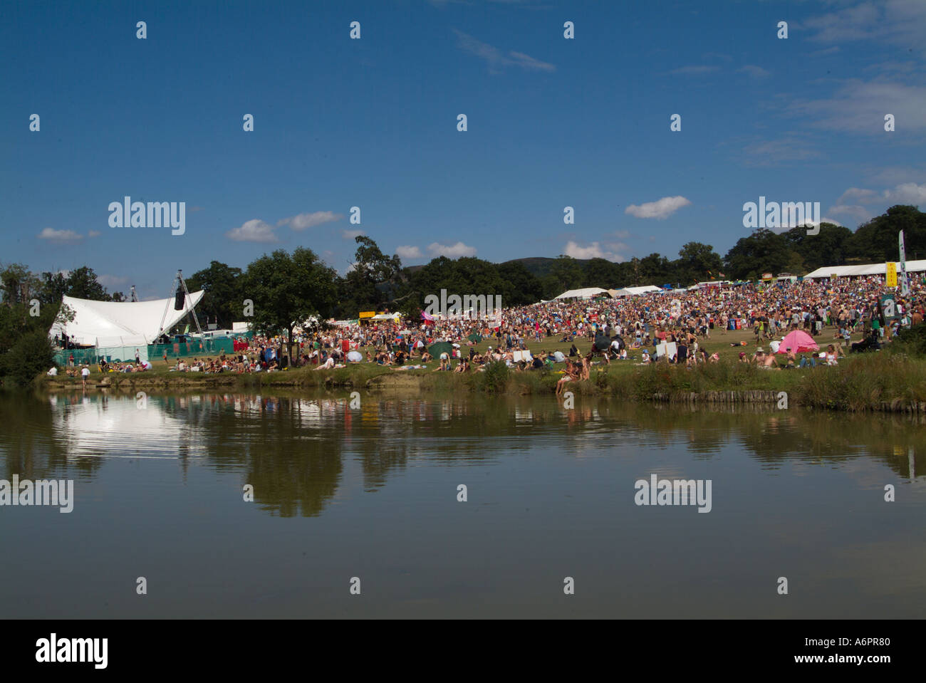 La folla dei frequentatori di partito si riflette nel lago al Big Chill festival di danza e musica Foto Stock