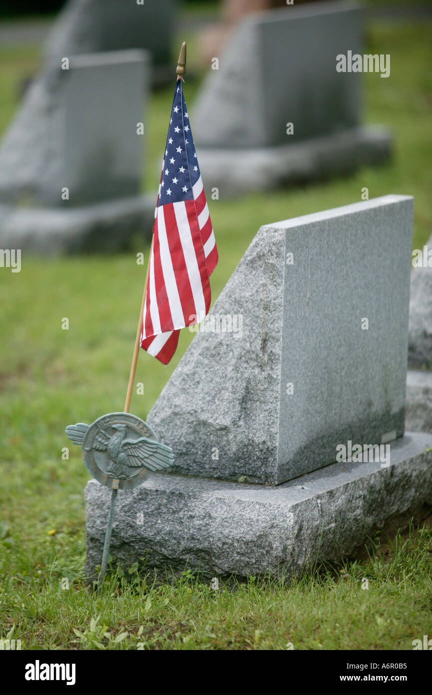 Bandiera degli Stati Uniti d'America resto accanto a una testa in pietra di una tomba di un veterano delle forze armate in un cimitero Foto Stock