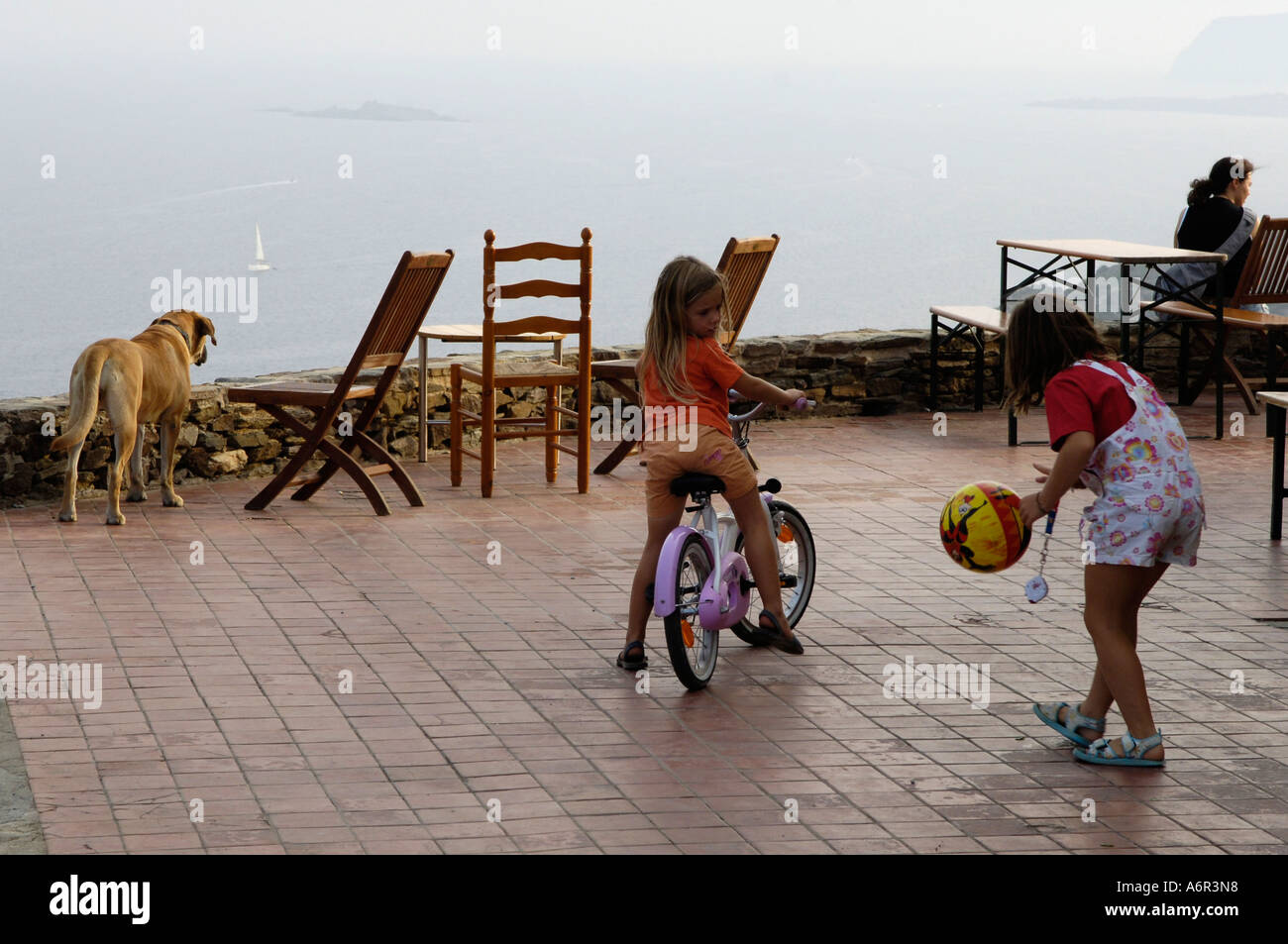 Ragazza in bici giocare a palla con un'altra ragazza Foto Stock