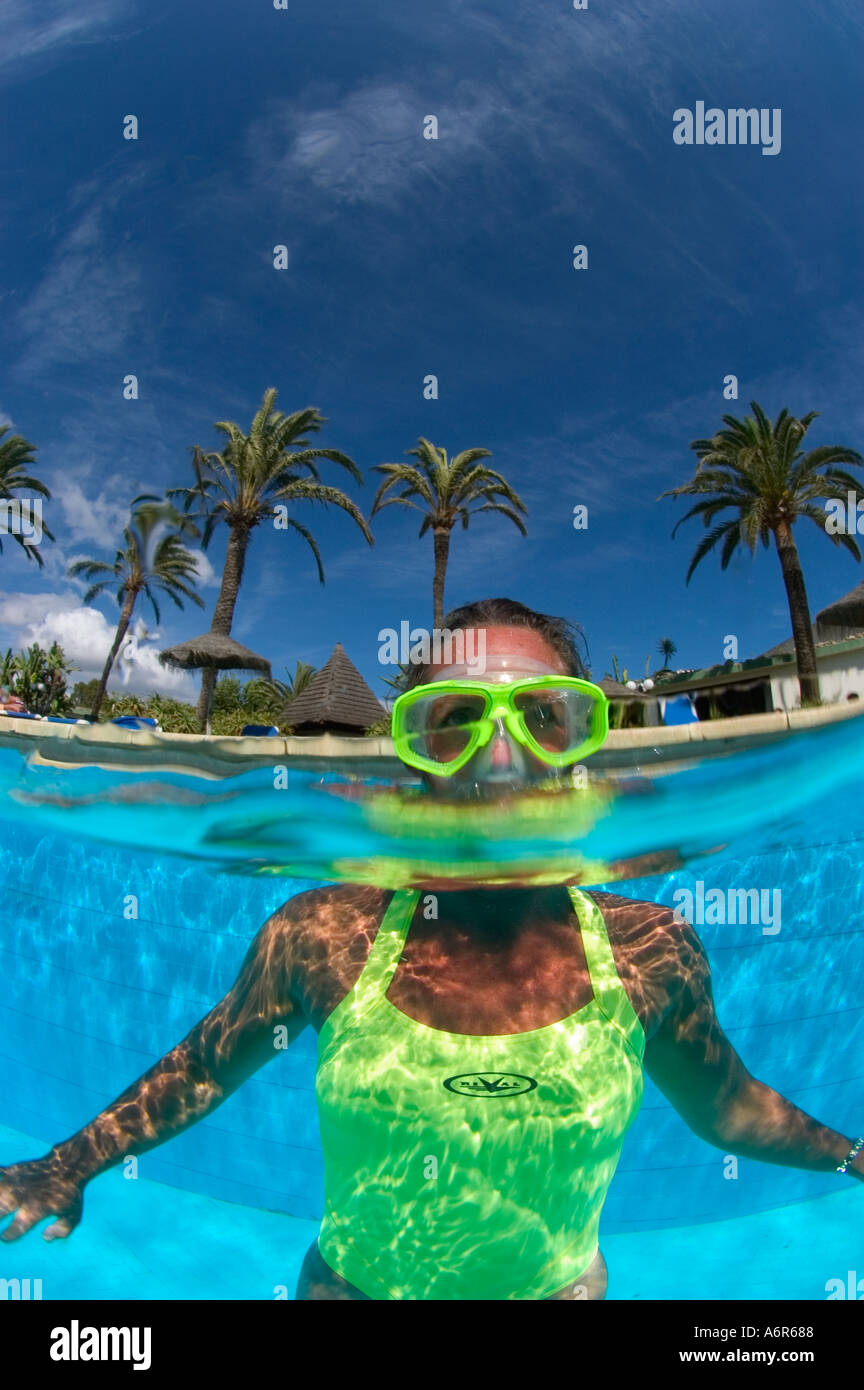 Split shot in piscina con snorkeller in tuta gialla e palme Foto Stock