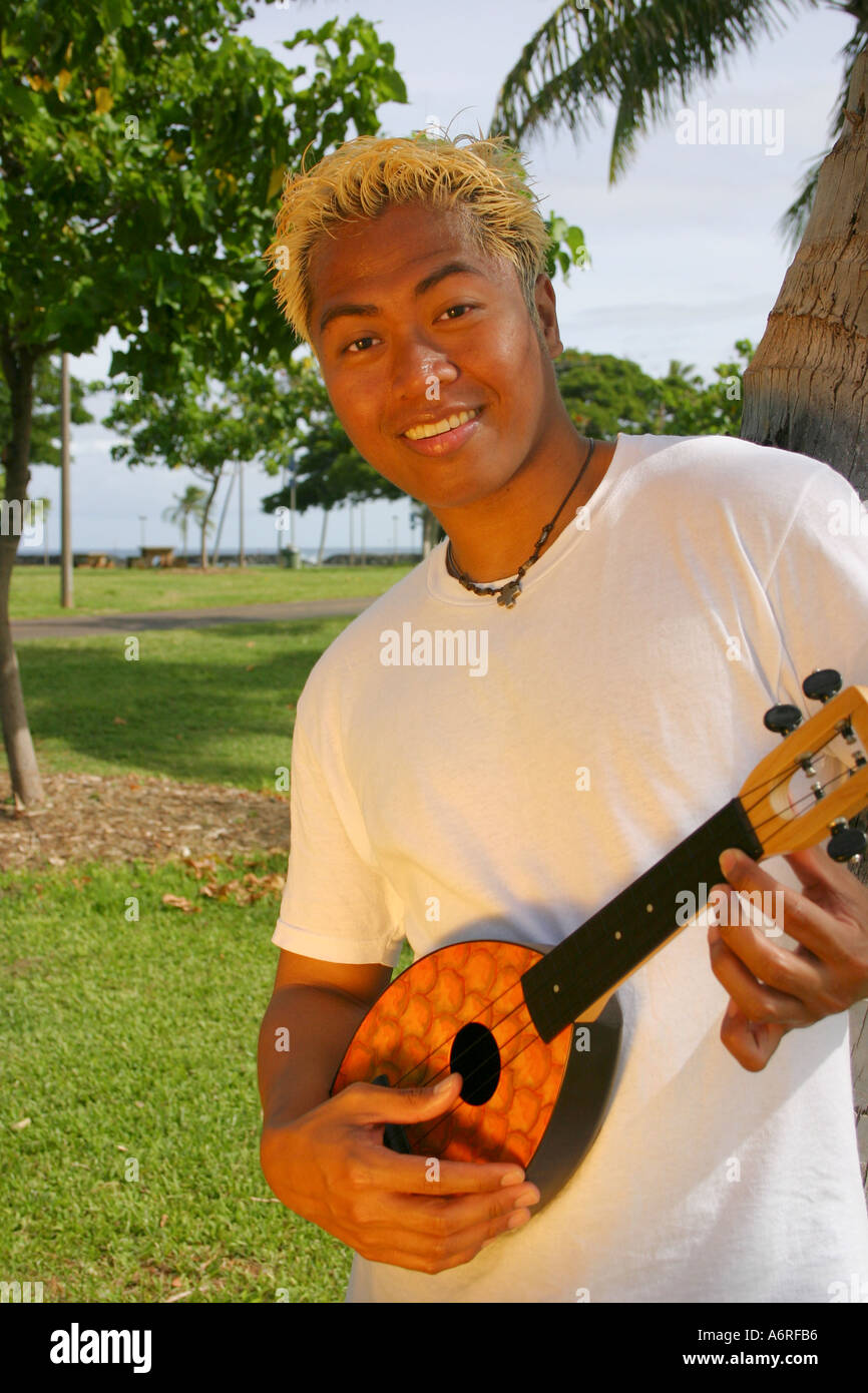 Giovane uomo hawaiano giocando ukulele sotto il palm tree Hawaii Foto Stock
