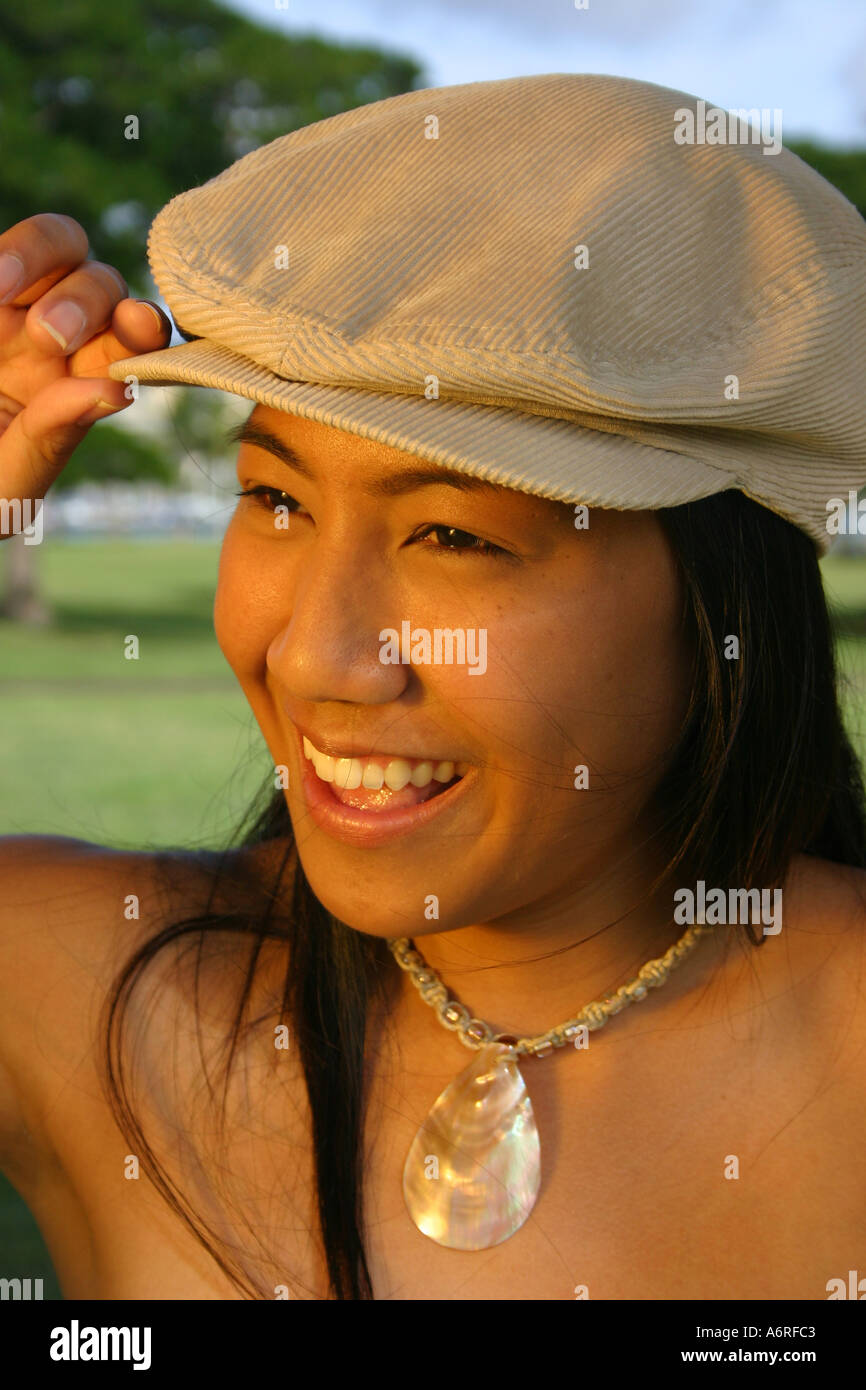 Giovane donna hawaiano in abbigliamento casual e hat e collana sorridente Foto Stock