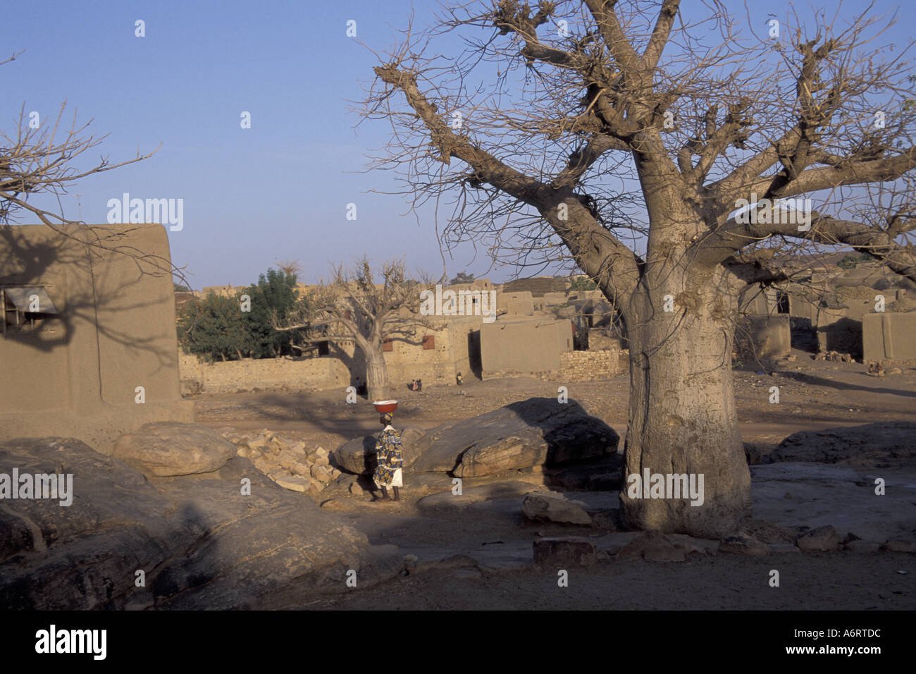 Africa, Mali, Regione Dogon, villaggio Segou. Donna che cammina con ciotola sulla testa Foto Stock