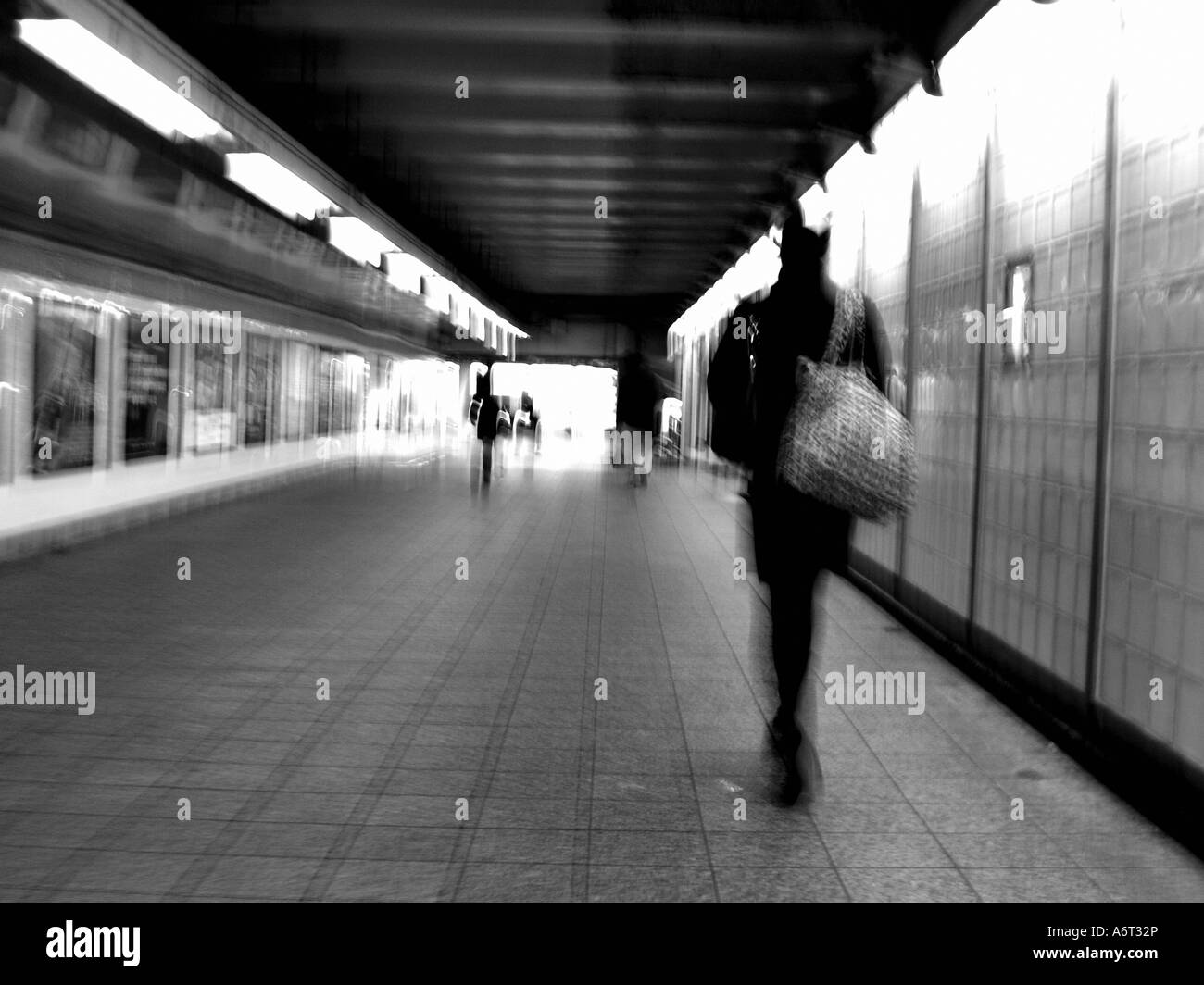 Di " commuters " femmina a piedi attraverso gli illuminati Times Square stazione della metropolitana a tarda notte, con motion blur, in bianco e nero. Foto Stock