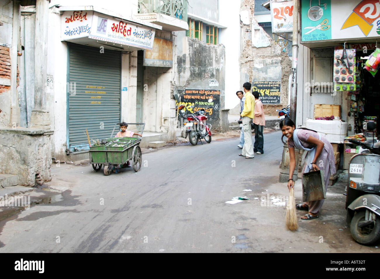 Spazzatrice stradale con il suo bambino contribuendo a spingere il rifiuto cart.Gujarat India Foto Stock