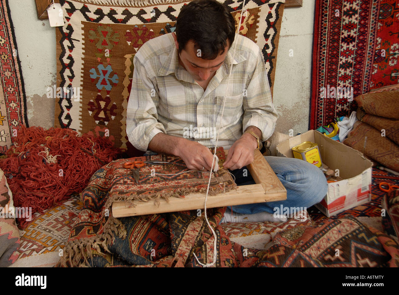 Un tessitore lavora su un tappeto tradizionale in un laboratorio di tessitura di tappeti ad Antalya in Turchia Foto Stock