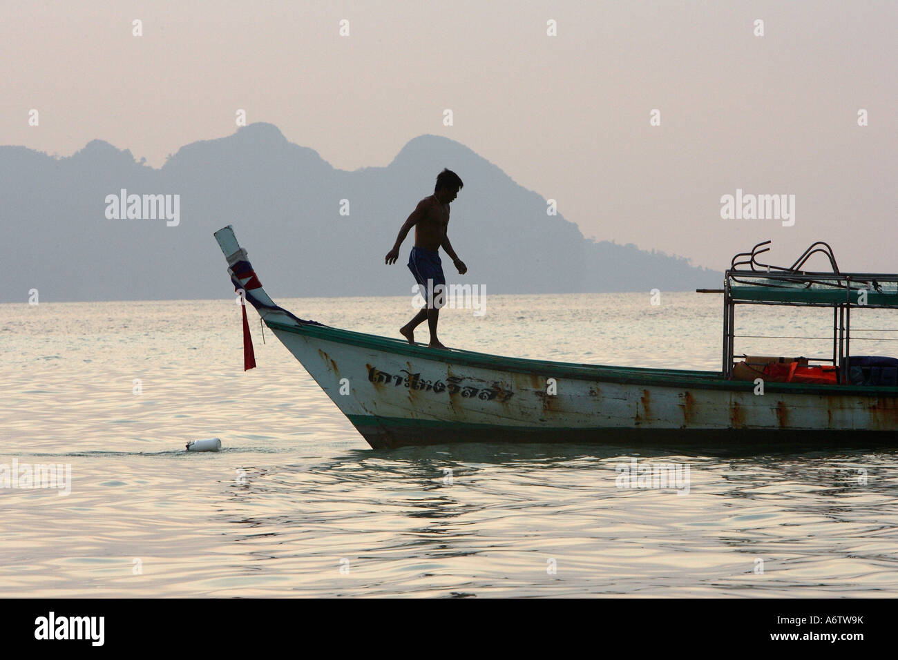 Longtail boat capitano sulla sua barca all'alba - Mare delle Andamane di fronte l'isola di Koh Ngai Koh (HAI) in Thailandia, Asia Foto Stock