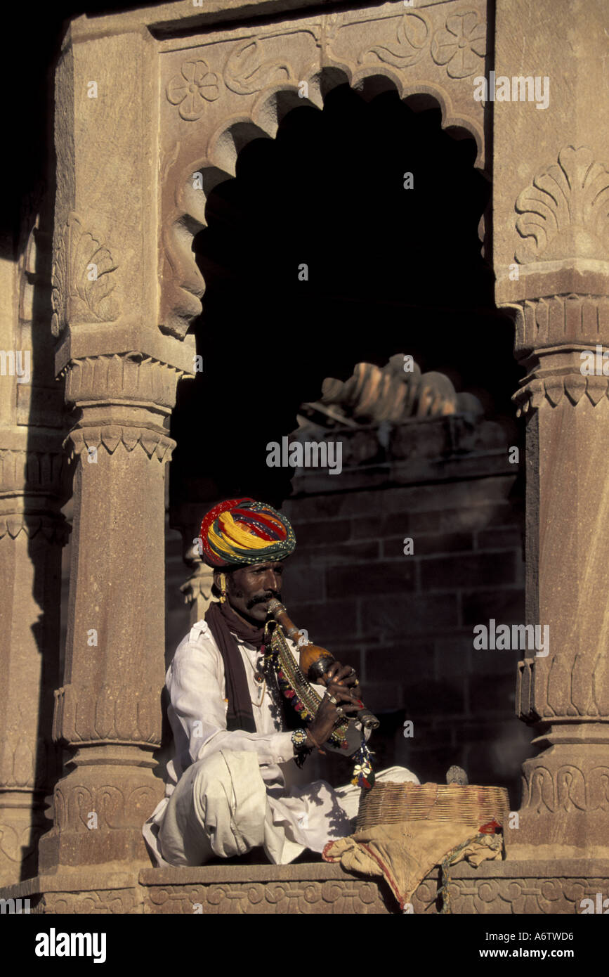 ASIA, India, Jodphur, Rajasthan, locale indiana incantatore di serpente seduto sotto arco in pietra, (MR) Foto Stock