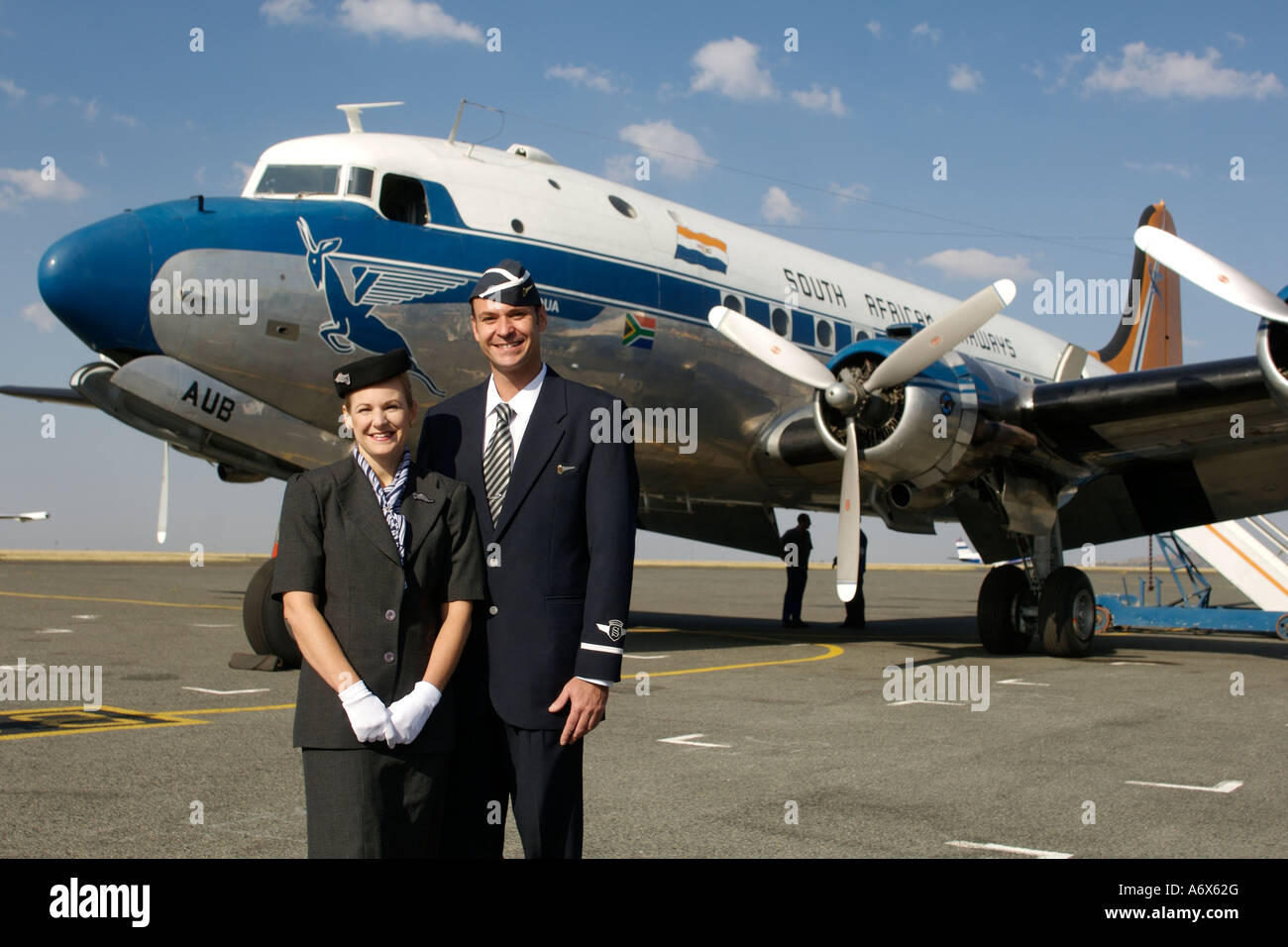 Equipaggio di cabina in tradizionale degli anni cinquanta uniformi in piedi accanto ad un vecchio South African Airways DC-4. Foto Stock