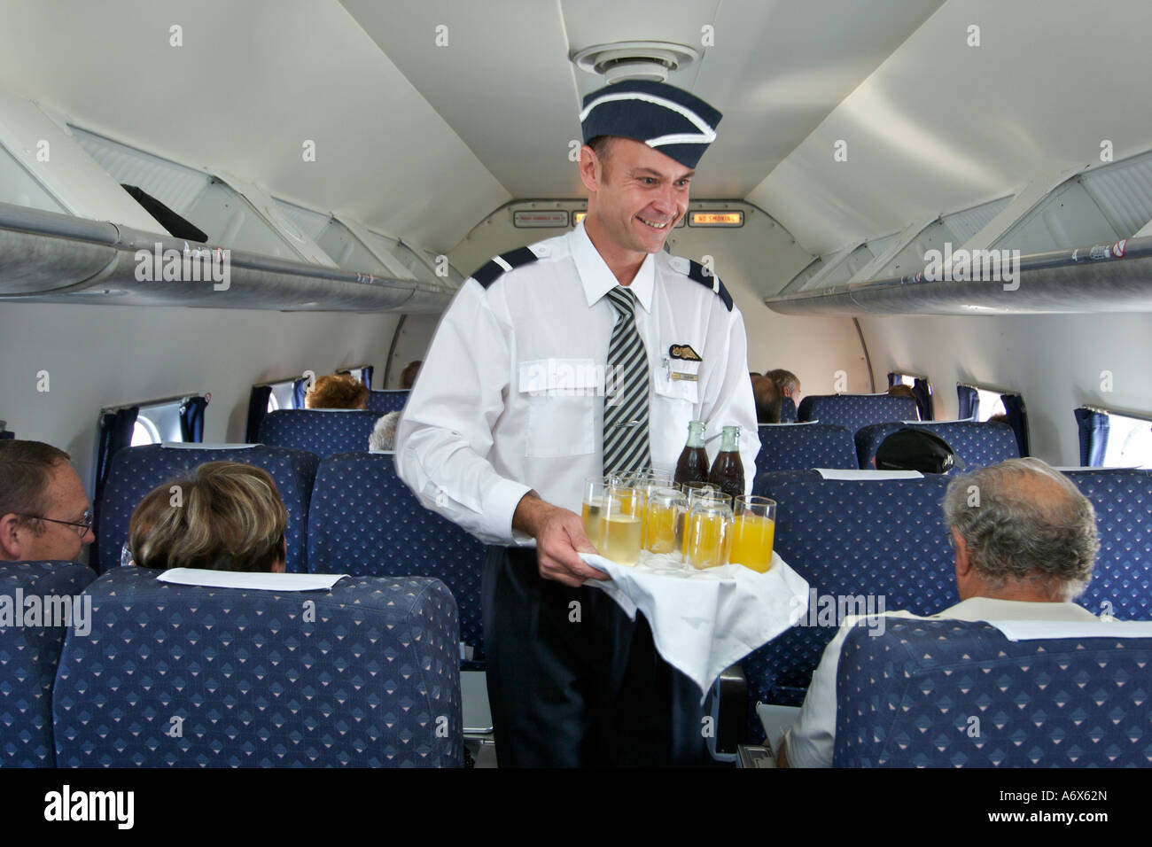 Un maggiordomo che serve bevande ai passeggeri a bordo di un vecchio DC-4. Foto Stock