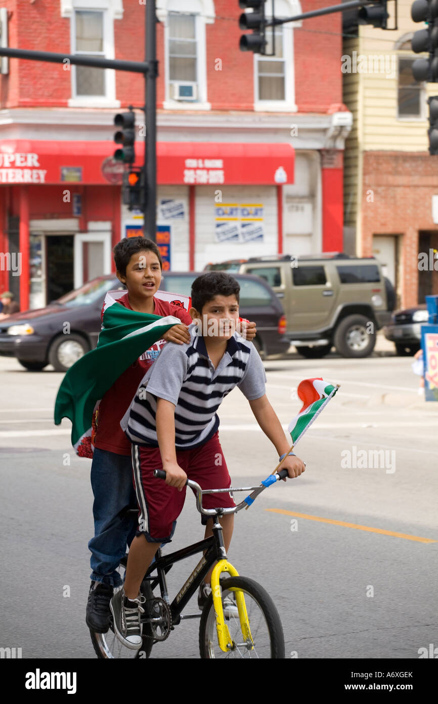ILLINOIS Chicago messicano due ragazzi in bicicletta insieme detengono bandierine messicane Giorno Di Indipendenza nel quartiere Pilsen Foto Stock