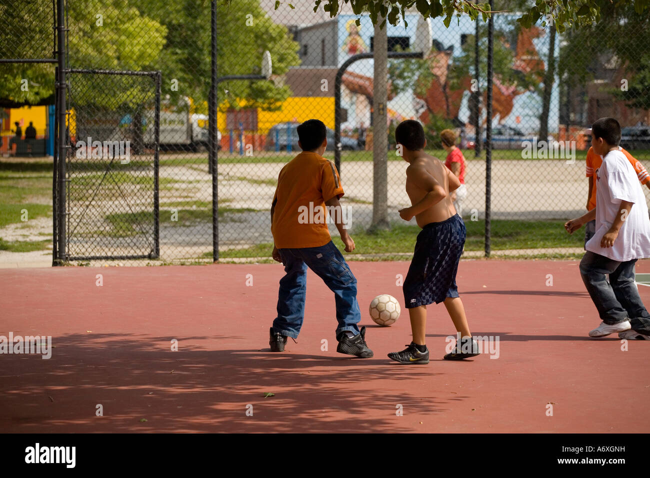 ILLINOIS Chicago Boys giocare a calcio sul campo da tennis Parco nel quartiere Pilsen Foto Stock