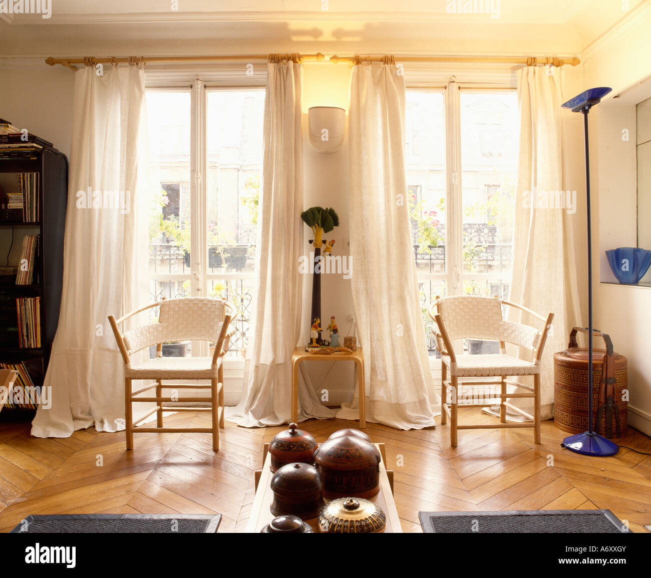 Sedie bianche con cornici di legno di fronte a finestre alte con drappi  crema nel salone con legno parquet Foto stock - Alamy