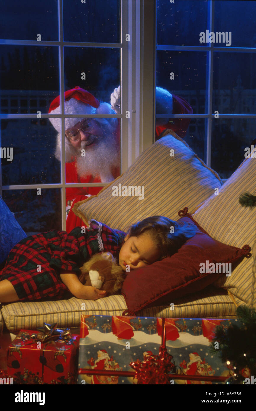 Santa Claus spiata nella finestra al giovane ragazza addormentata della vigilia di Natale presenta inverno AK Foto Stock