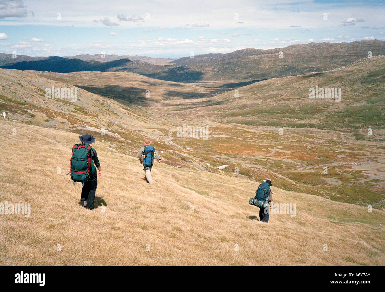 Tre persone backpacking attraverso colline Foto Stock