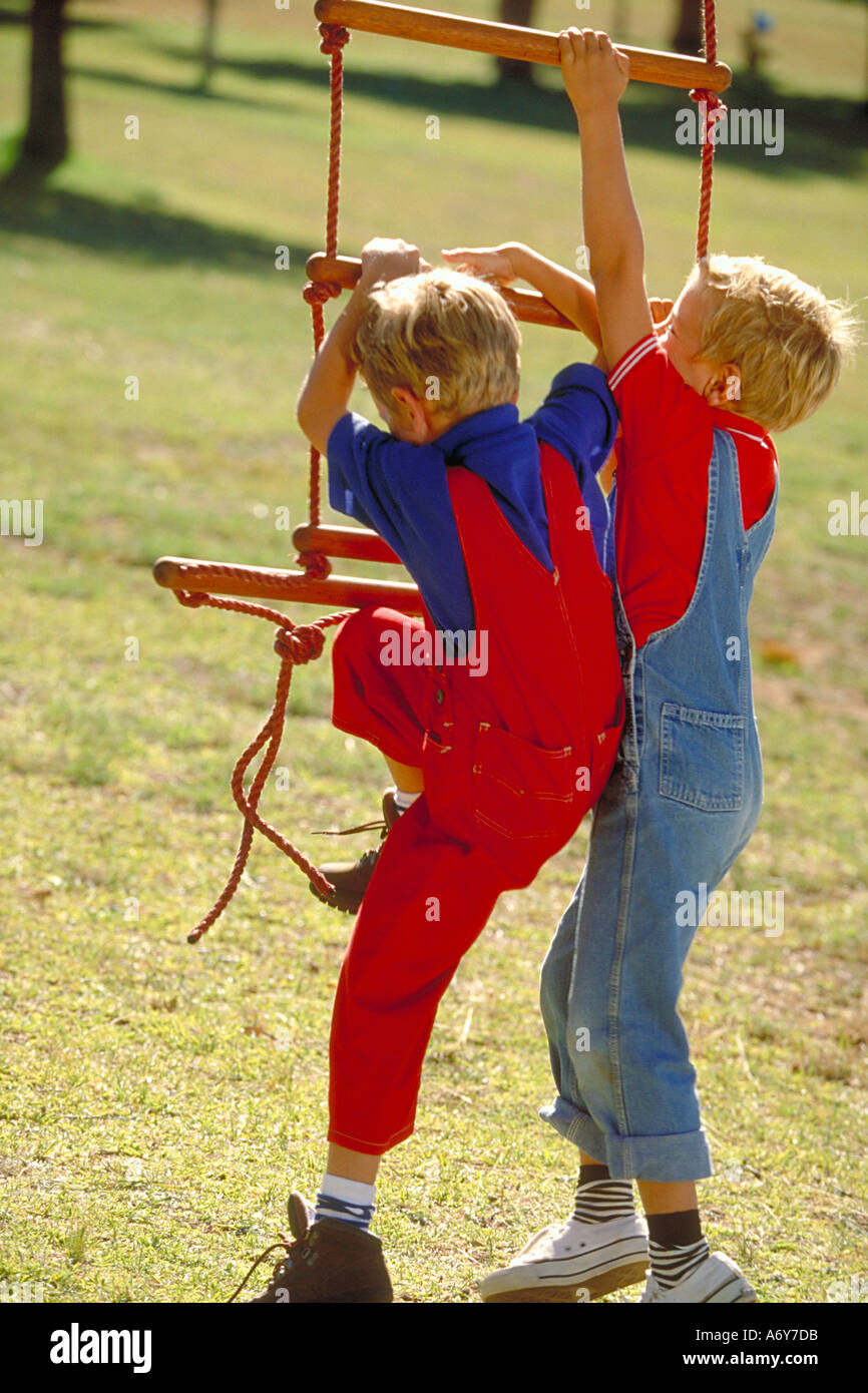 Ritratto di due fratelli gemelli giocando su una scaletta di corda Foto Stock