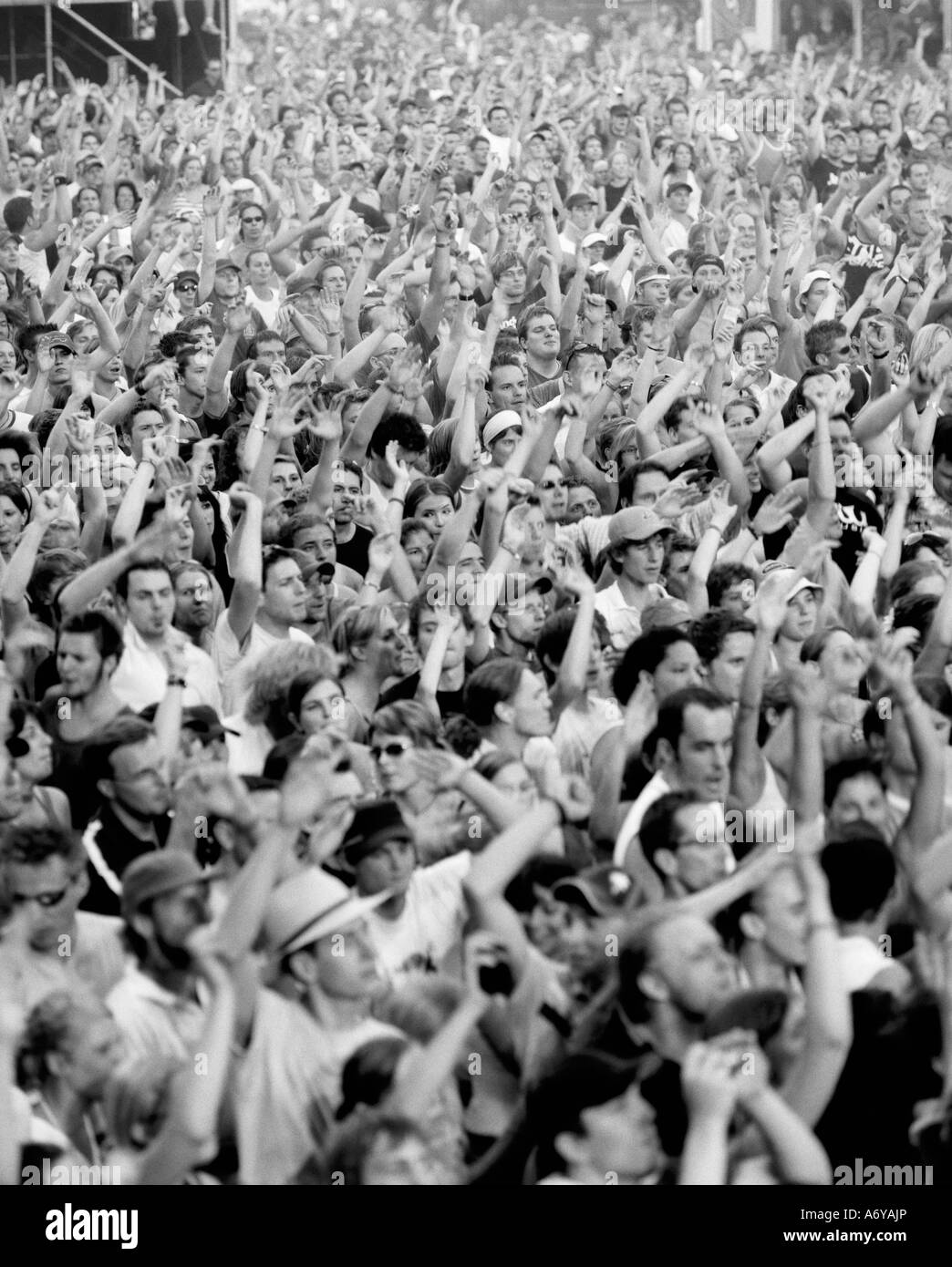 Grande folla di persone con le braccia alzate Foto Stock
