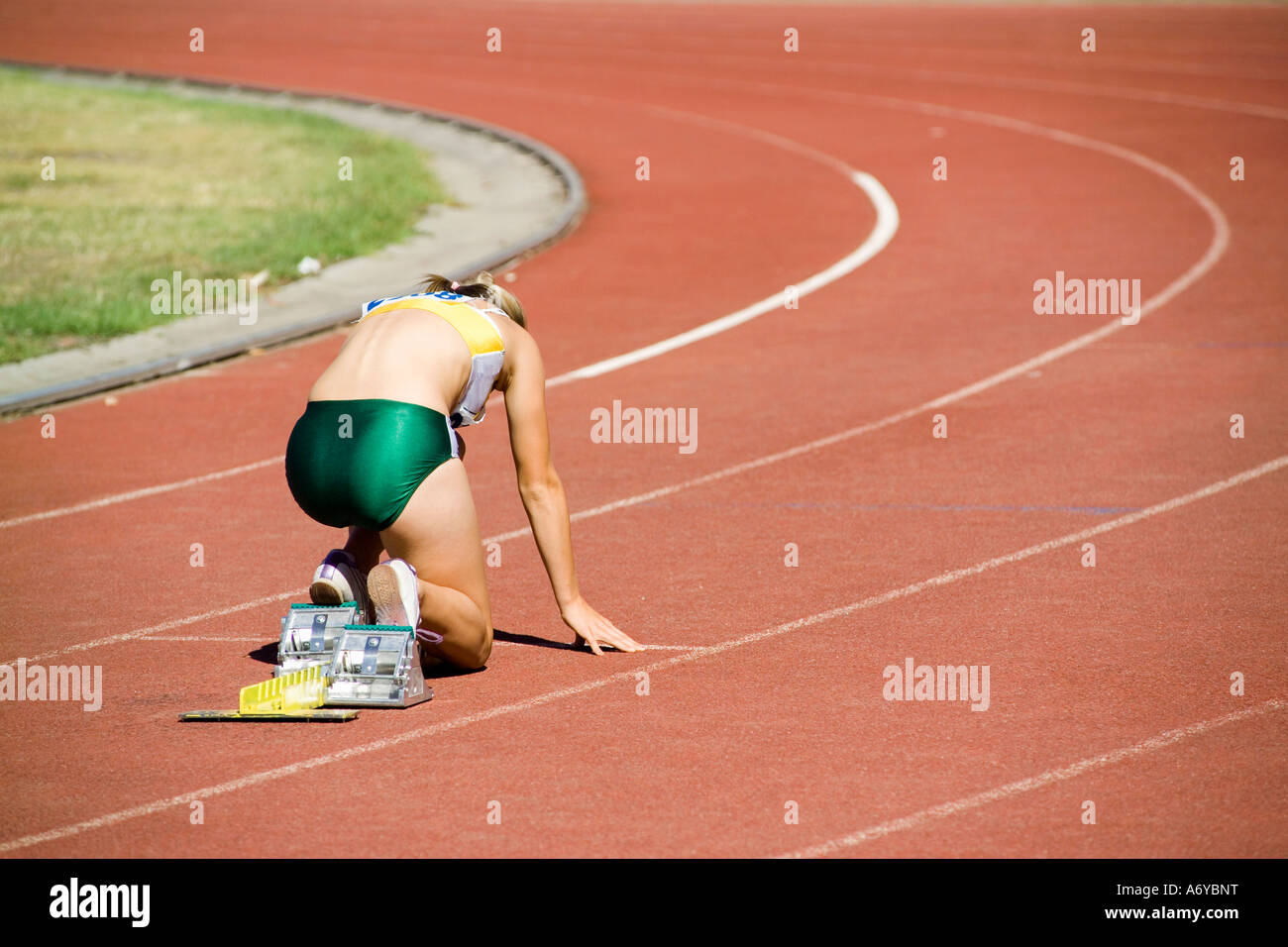 Atleta femminile in blocchi di partenza su una via di corsa Foto Stock