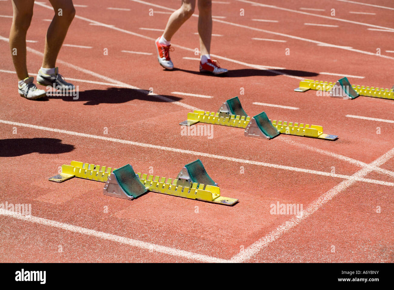 Gli uomini in piedi dietro i blocchi di partenza all'inizio di una corsa Foto Stock