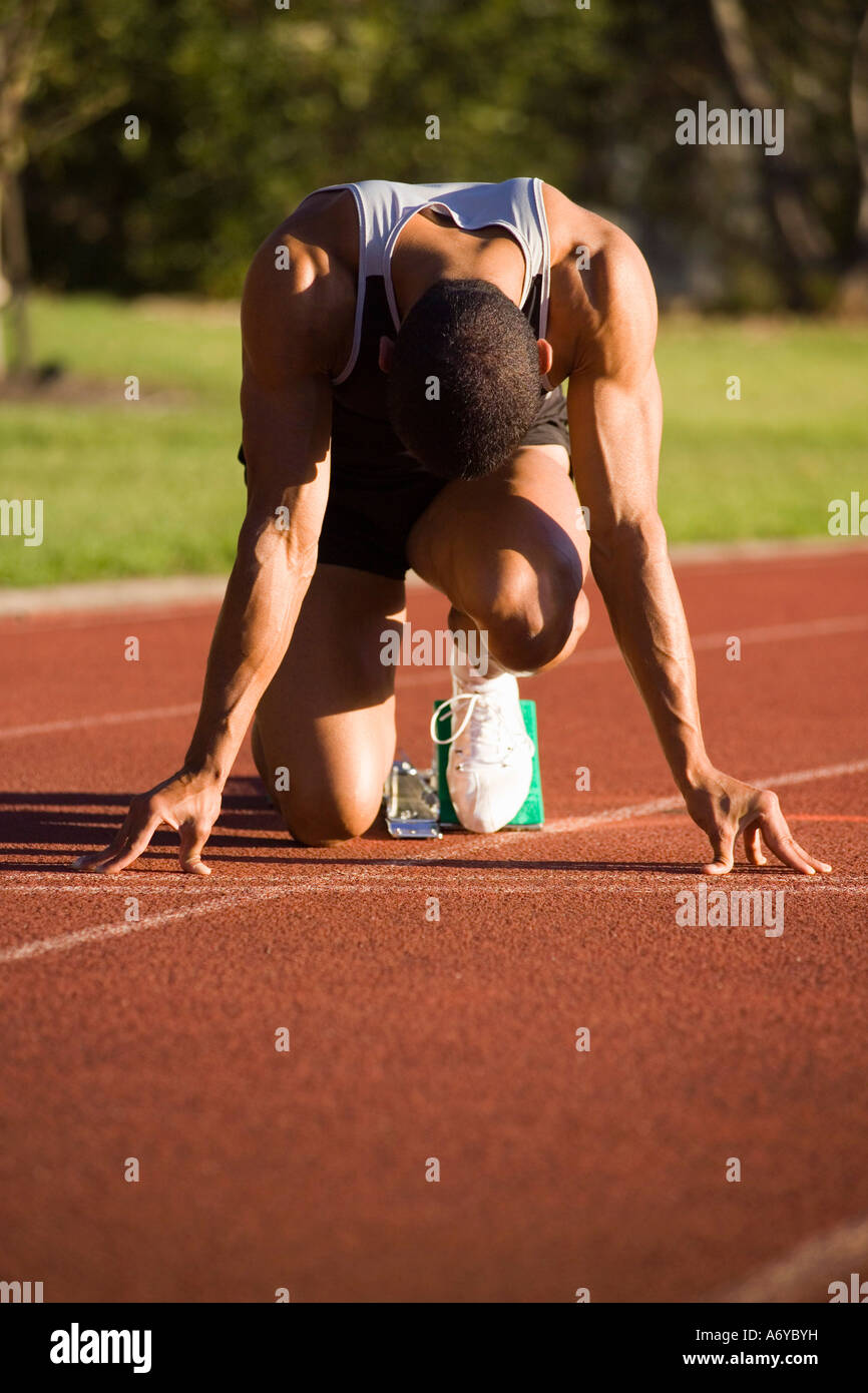 Atleta maschio in blocchi di partenza su una via di corsa Foto Stock