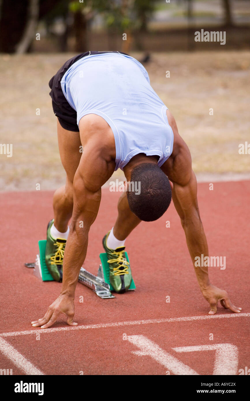 Atleta maschio in blocchi di partenza su una via di corsa Foto Stock