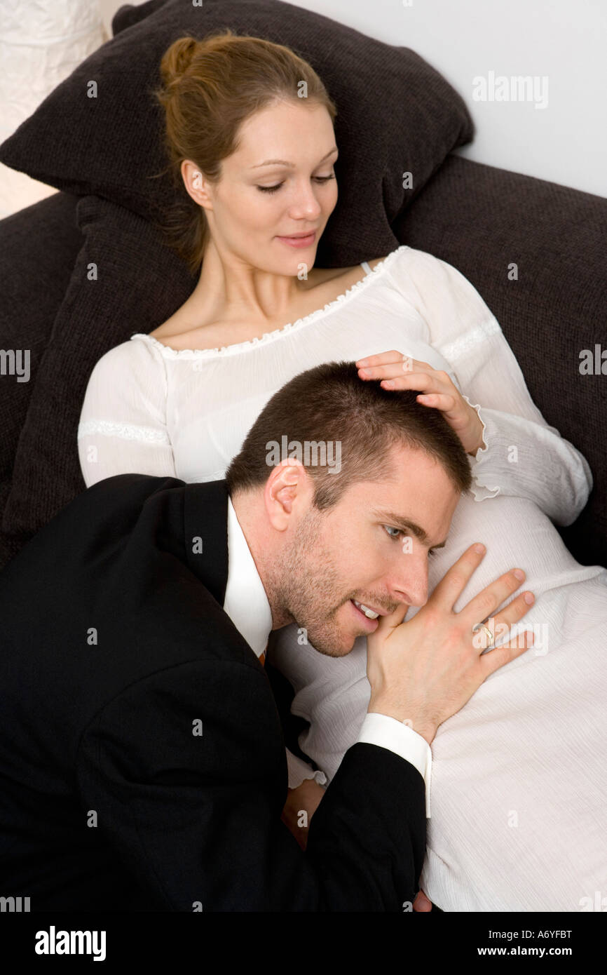 L'uomo mettendo la sua testa fino ad una donna in stato di gravidanza s stomaco Foto Stock