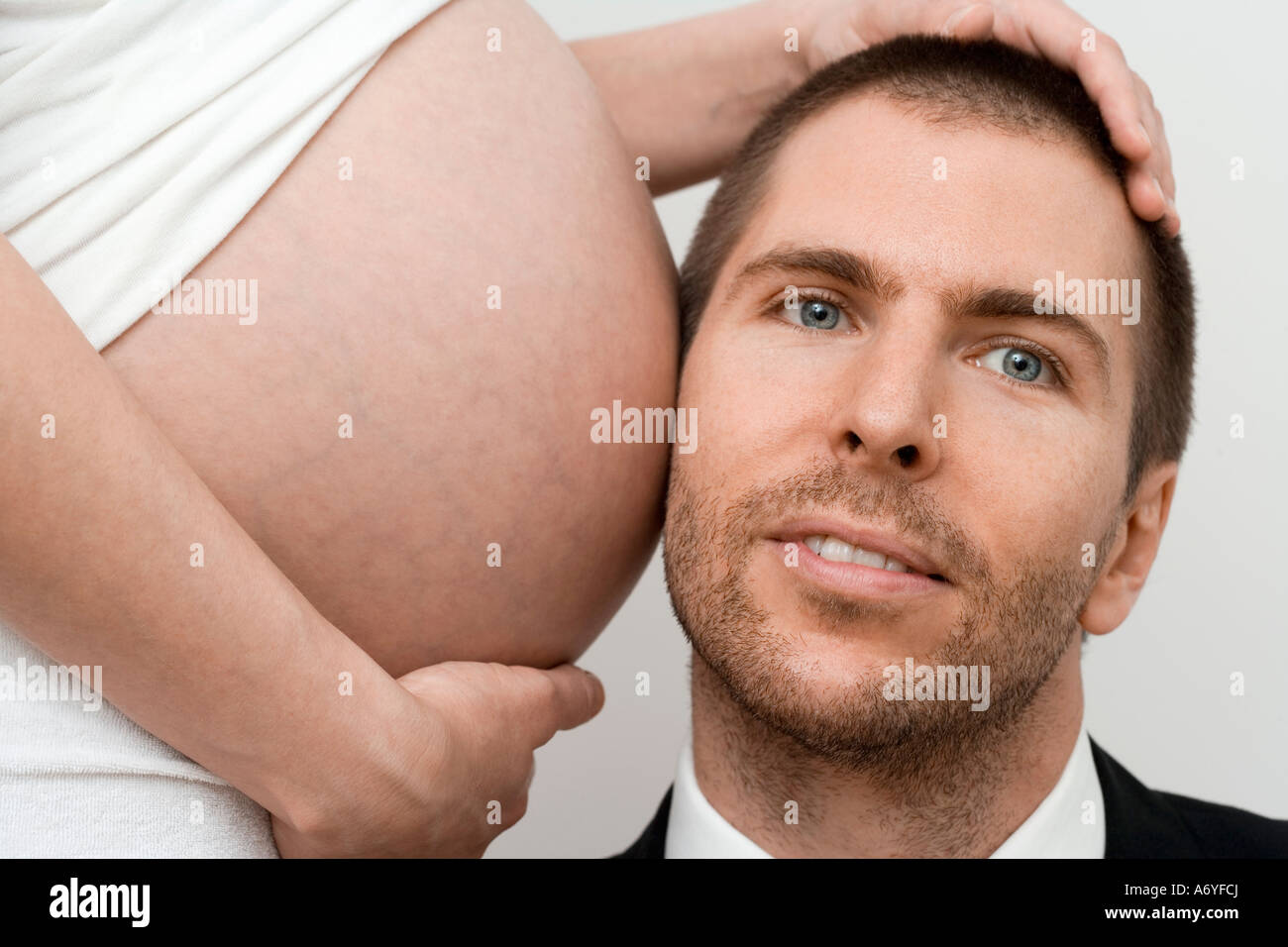 L'uomo mettendo la sua testa fino ad una donna in stato di gravidanza s stomaco Foto Stock