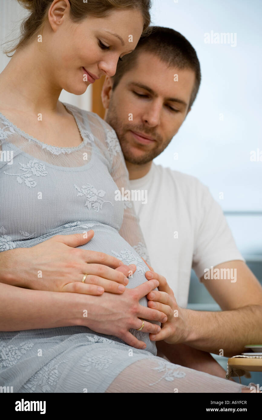 Donna incinta seduta su un uomo s lap Foto Stock