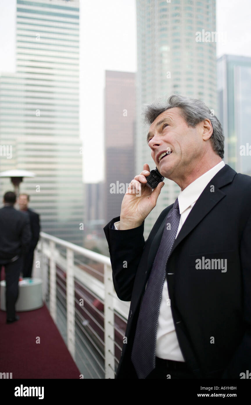 Imprenditore in piedi su una terrazza sul tetto con un telefono cellulare Foto Stock