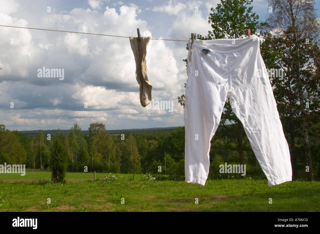 Un paio di calze e pantaloni appesi ad asciugare su una linea di vestiti con  abiti perni un giorno di estate con le nuvole nel cielo. Smaland ri Foto  stock - Alamy