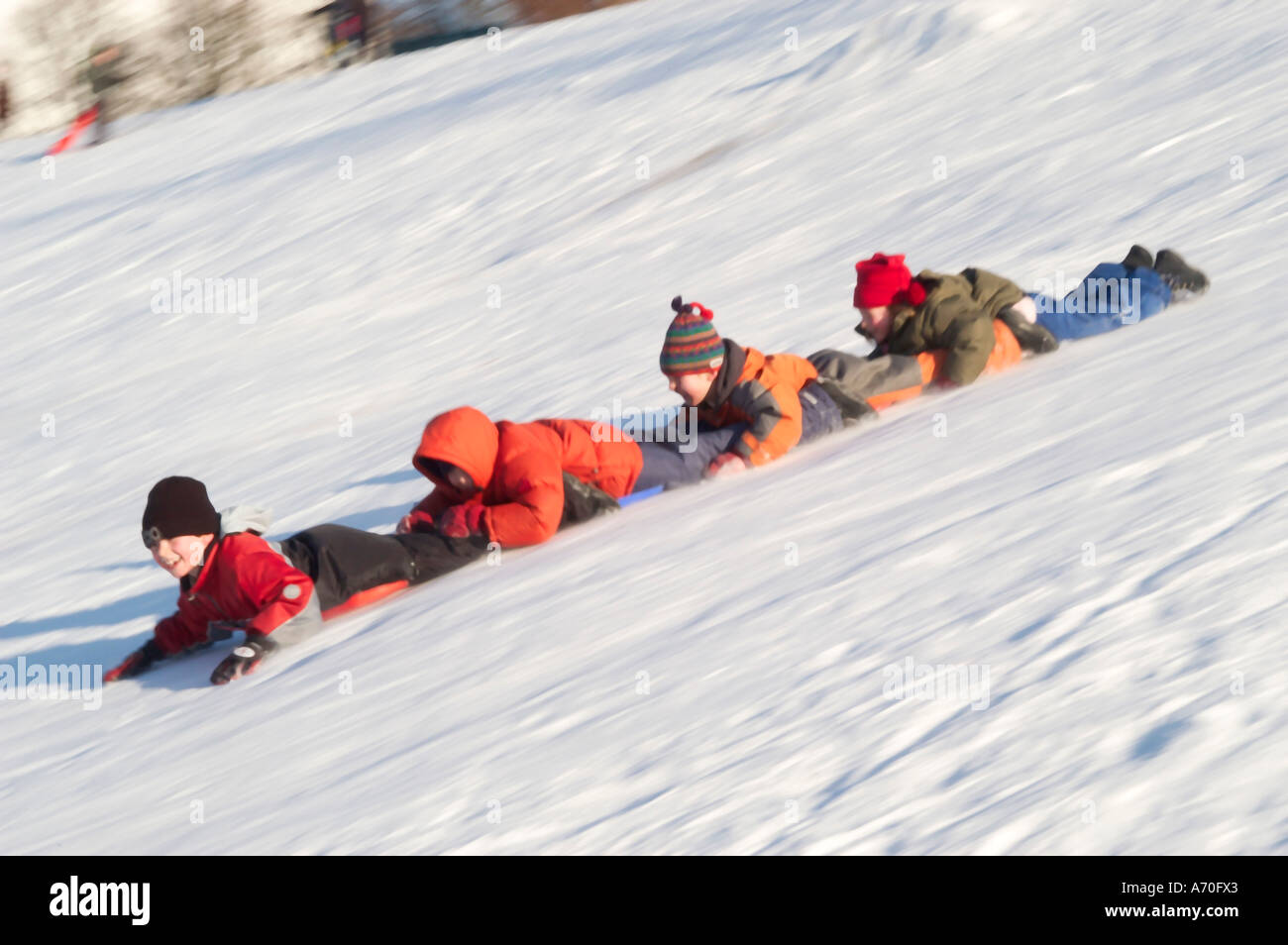 Catena di scorrimento dei bambini sul loro pance in discesa Foto Stock