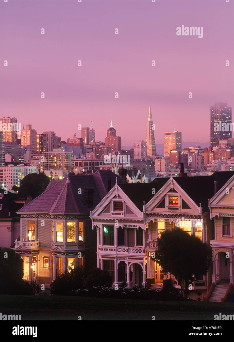 Case in stile vittoriano su Steiner Street al tramonto a San Francisco con lo skyline della citta' oltre Foto Stock