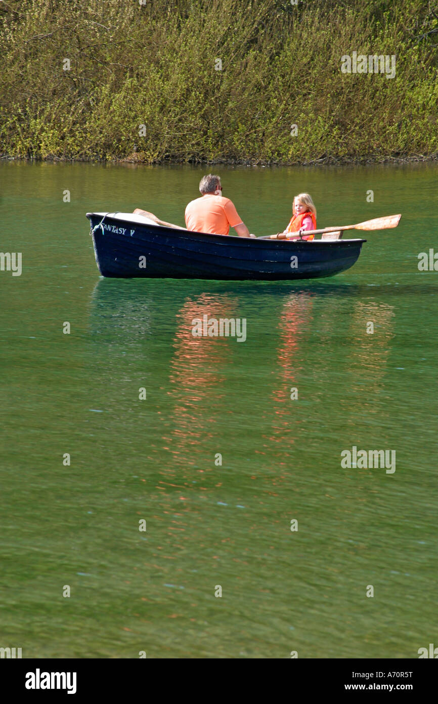 Padre con figlia giovane in barca a remi sul lago di piacere. Swanbourne Lake, Arundel, West Sussex, Inghilterra Foto Stock