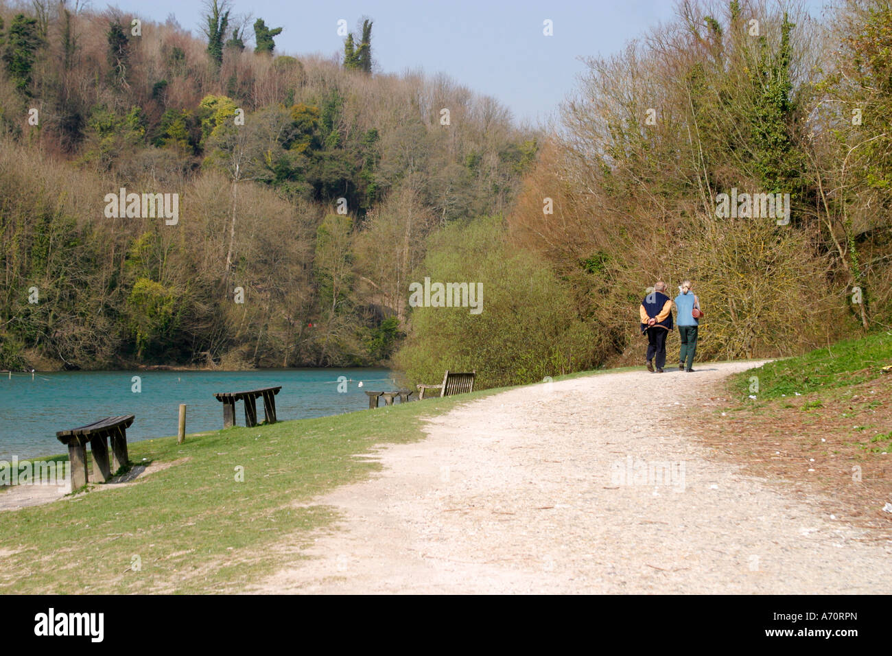 L uomo e la donna a piedi attorno al bordo del lago Swanbourne, Arundel, Sussex, Regno Unito Foto Stock