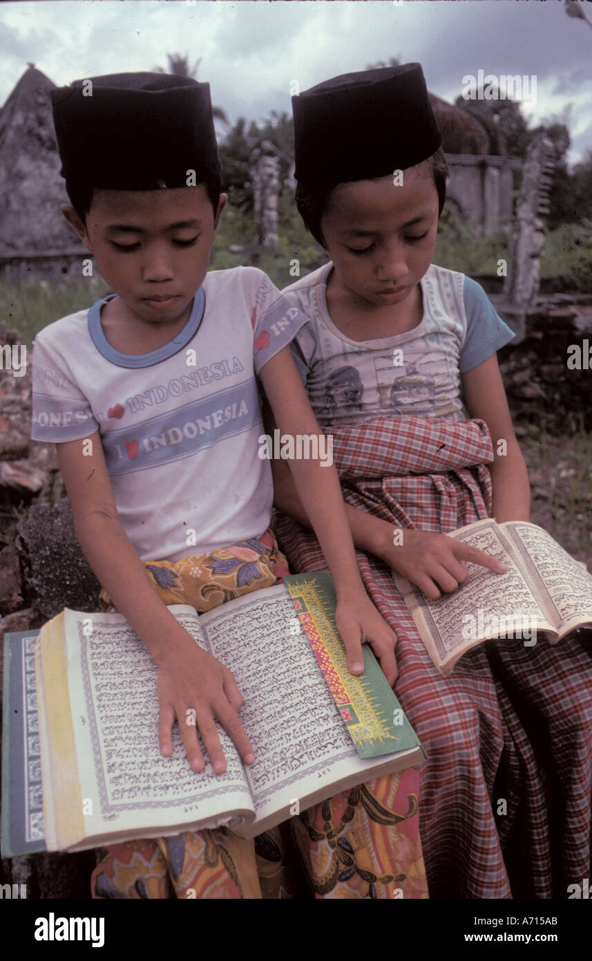 Ragazzi musulmani che leggono il Corano in un cimitero indonesiano Foto Stock